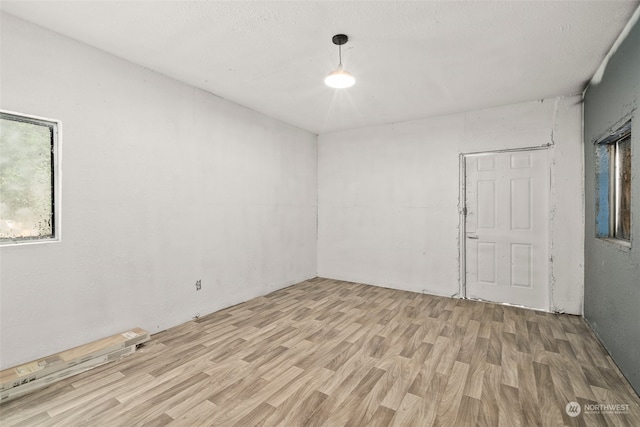 empty room featuring a textured ceiling and light hardwood / wood-style flooring