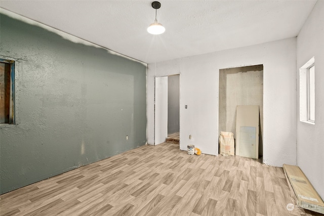 unfurnished bedroom with a textured ceiling and light hardwood / wood-style flooring