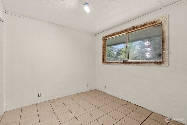 empty room featuring a textured ceiling and light tile patterned floors