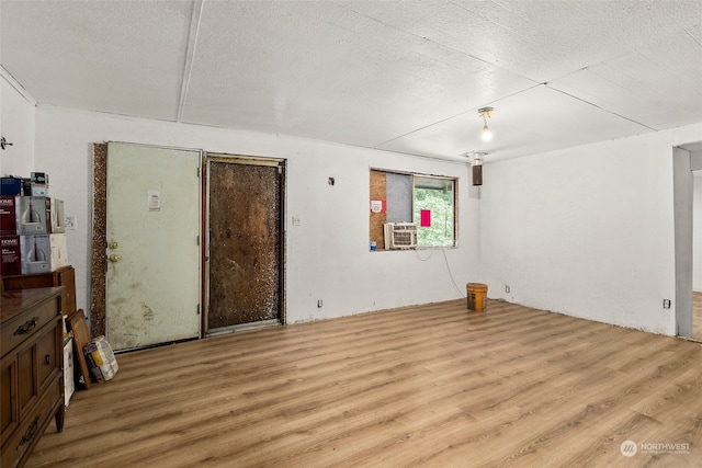 unfurnished room with a textured ceiling, cooling unit, and light hardwood / wood-style floors