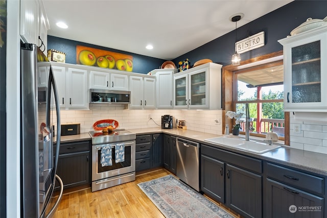 kitchen featuring light hardwood / wood-style flooring, sink, hanging light fixtures, appliances with stainless steel finishes, and white cabinets