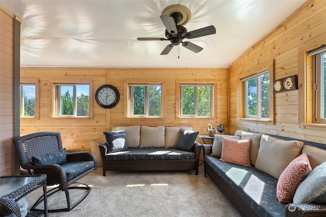 living room featuring carpet flooring, ceiling fan, and wooden walls