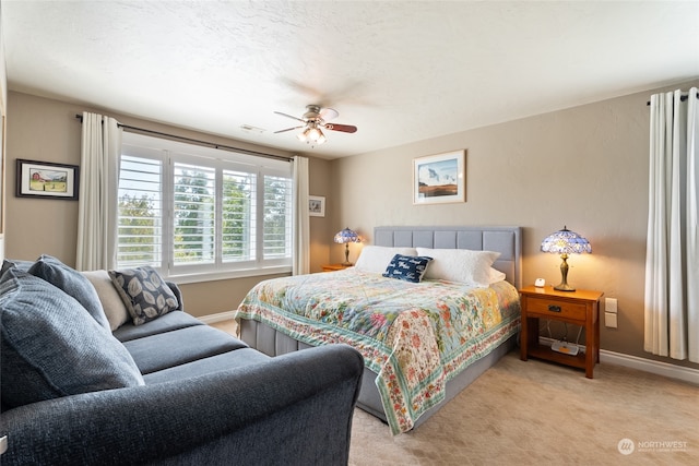 carpeted bedroom featuring ceiling fan and a textured ceiling