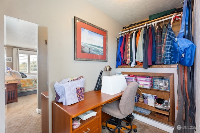 carpeted home office featuring a textured ceiling