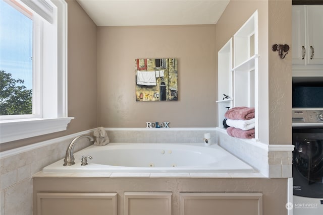 bathroom with washer / dryer and a bathing tub