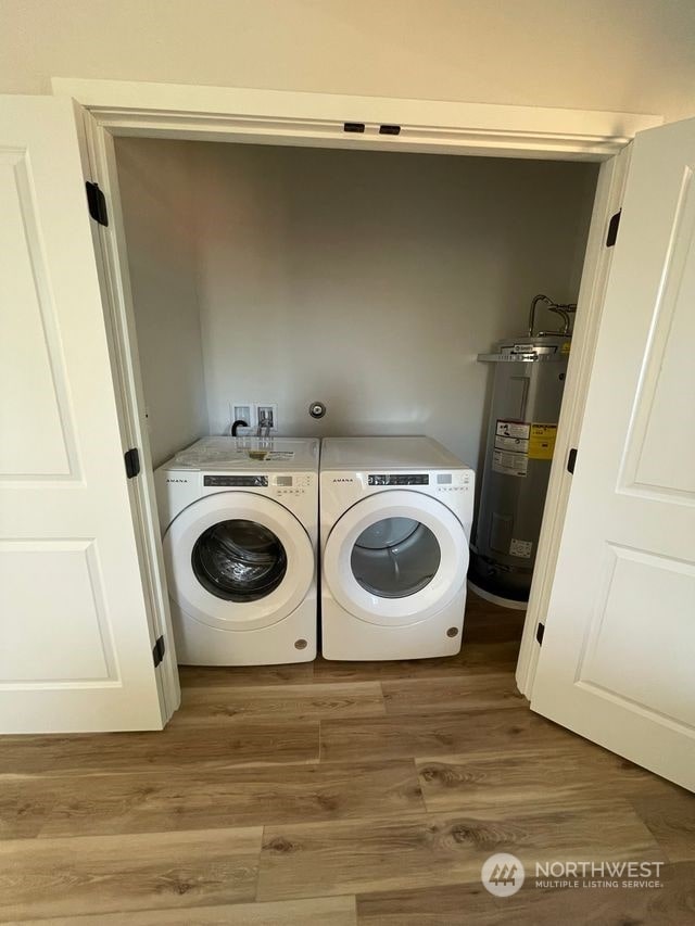 laundry area with washer and clothes dryer, hardwood / wood-style floors, and water heater