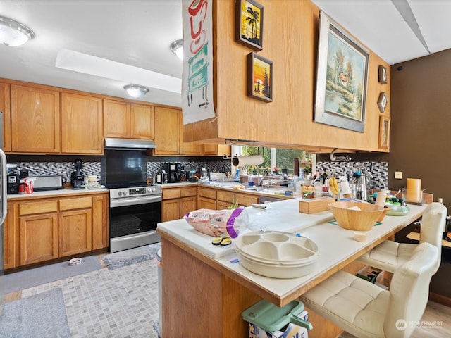 kitchen with stainless steel range with electric stovetop, a kitchen bar, kitchen peninsula, and tasteful backsplash