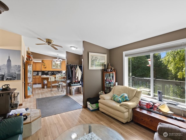 living room featuring light hardwood / wood-style floors, ceiling fan with notable chandelier, and lofted ceiling