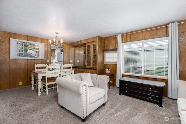 living room featuring wood walls, an inviting chandelier, a textured ceiling, and carpet floors