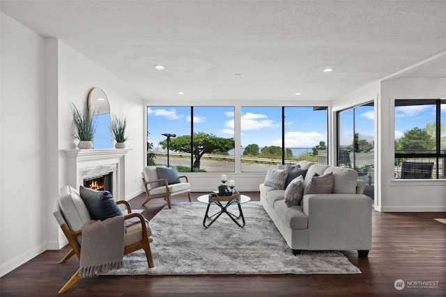 living area featuring a high end fireplace, baseboards, recessed lighting, wood finished floors, and a textured ceiling