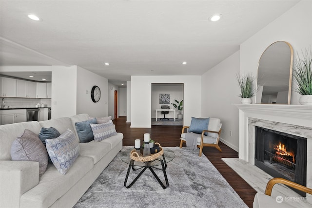living room featuring recessed lighting, a fireplace, dark wood-style flooring, and baseboards
