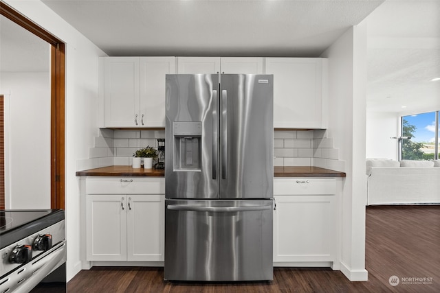 kitchen with appliances with stainless steel finishes, butcher block counters, dark wood finished floors, and tasteful backsplash