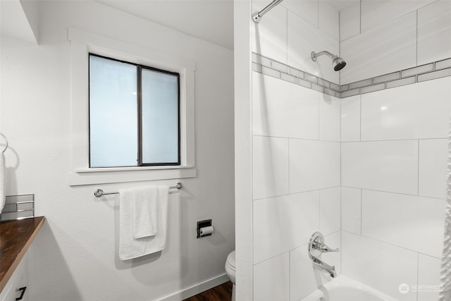 bathroom featuring toilet,  shower combination, wood finished floors, and baseboards