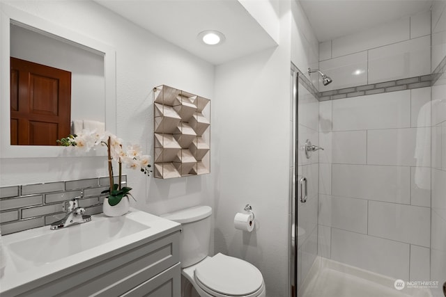bathroom with a shower stall, toilet, and vanity