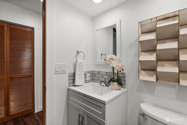 half bath with wood finished floors, toilet, and vanity
