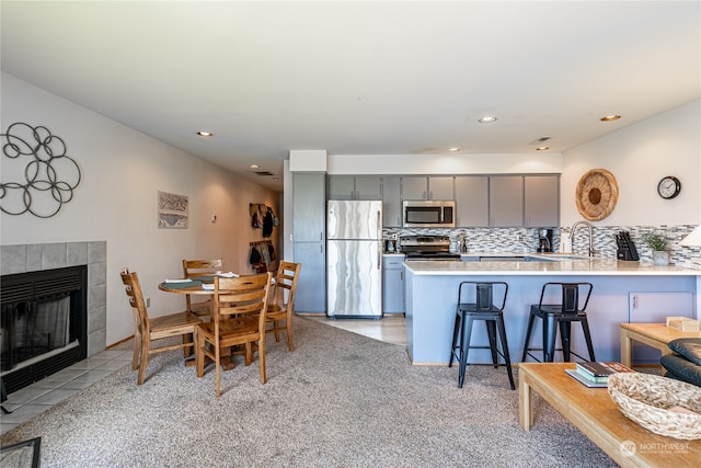 carpeted dining area with a tile fireplace and sink