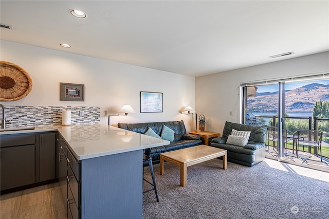 kitchen with tasteful backsplash, kitchen peninsula, a breakfast bar area, dark hardwood / wood-style floors, and sink