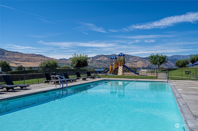 view of pool with a mountain view, a patio area, and a playground