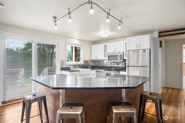 kitchen with a center island, white cabinetry, hardwood / wood-style floors, and stainless steel appliances