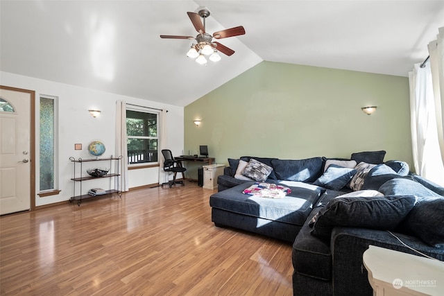 living room with ceiling fan, vaulted ceiling, built in desk, and light hardwood / wood-style floors