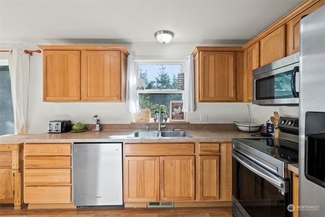 kitchen featuring appliances with stainless steel finishes, sink, and light hardwood / wood-style floors