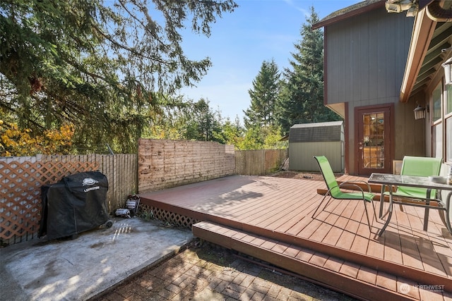 wooden deck featuring grilling area and a storage shed