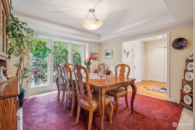 dining room featuring ornamental molding, wood-type flooring, and a raised ceiling