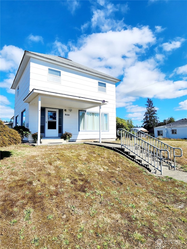 view of front of house with covered porch and a front lawn