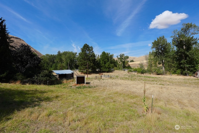 view of yard with a mountain view, a rural view, and an outdoor structure