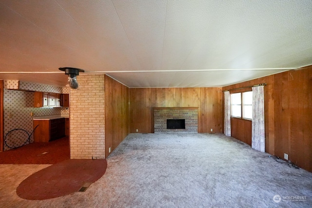 living room with dark carpet, wood walls, and a fireplace