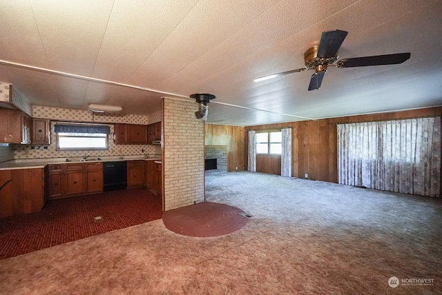 kitchen featuring dishwasher, ceiling fan, wood walls, and dark colored carpet