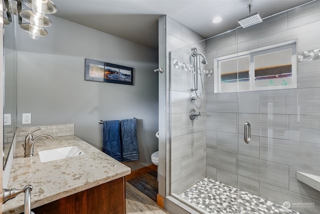 bathroom with vanity, hardwood / wood-style flooring, toilet, and a shower with shower door