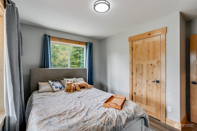 bedroom with dark hardwood / wood-style floors and a textured ceiling