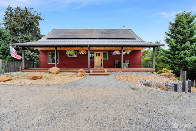 view of front of home featuring solar panels and covered porch