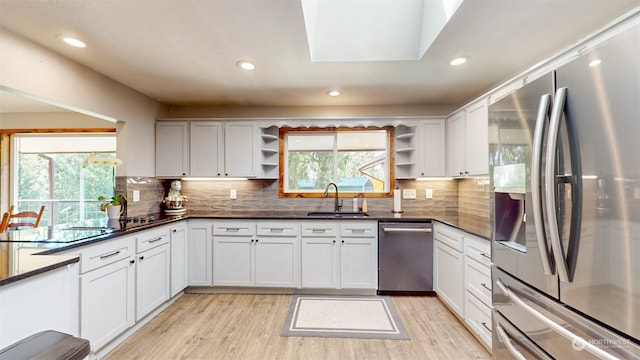 kitchen featuring appliances with stainless steel finishes, light wood-type flooring, a skylight, and a healthy amount of sunlight