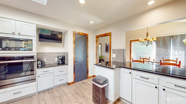 kitchen featuring backsplash, stainless steel oven, white cabinetry, and black microwave