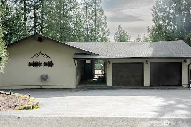 ranch-style house featuring a garage, roof with shingles, and aphalt driveway