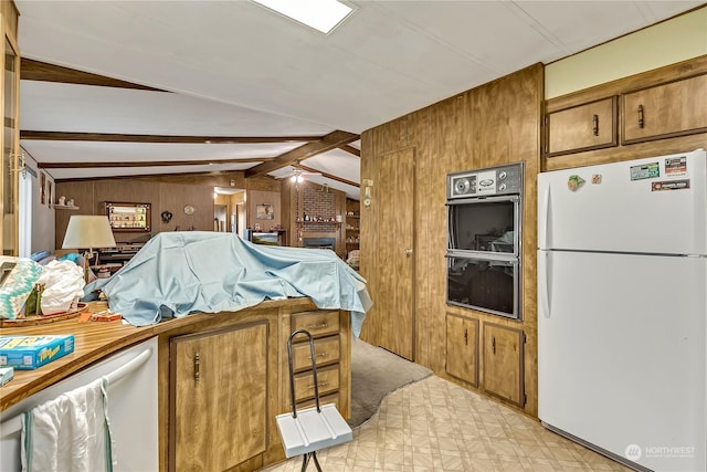 kitchen featuring dobule oven black, freestanding refrigerator, brown cabinetry, wood walls, and vaulted ceiling with beams