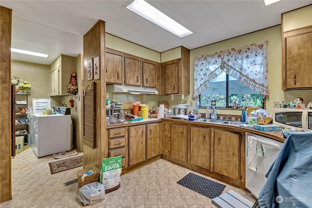 kitchen with washer / dryer, white appliances, light floors, under cabinet range hood, and brown cabinets