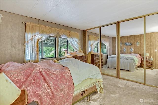 bedroom with two closets, wooden walls, carpet flooring, and multiple windows