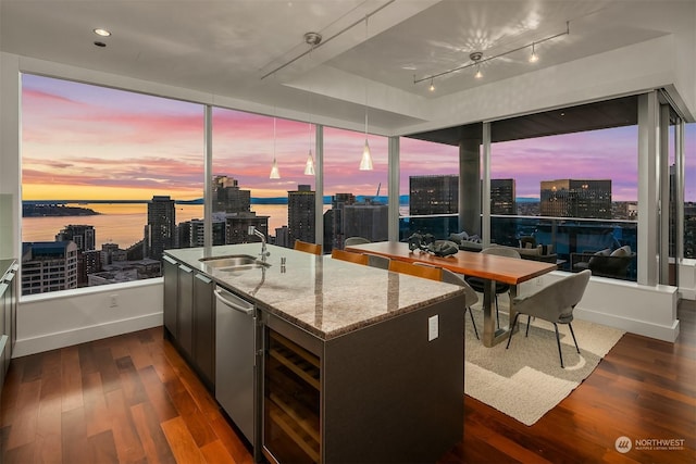 kitchen featuring dark hardwood / wood-style floors, dishwasher, sink, light stone counters, and a water view