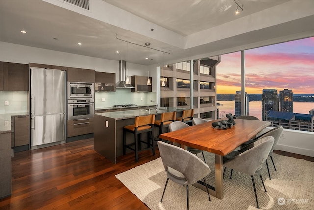 dining area with a water view, dark hardwood / wood-style floors, and sink