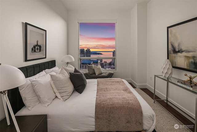 bedroom featuring dark wood-type flooring and a water view