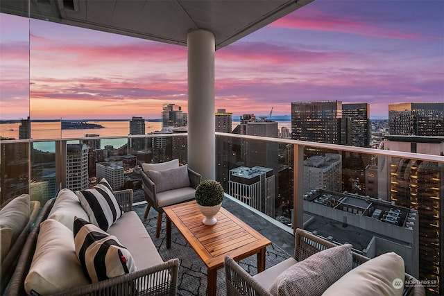 balcony at dusk featuring a water view and outdoor lounge area