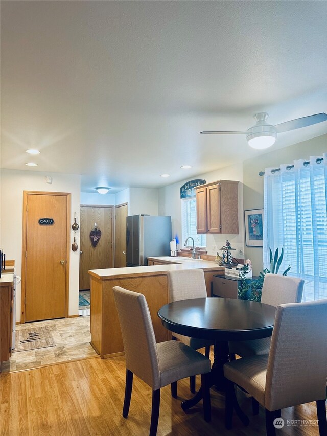 dining space with ceiling fan, sink, and light wood-type flooring