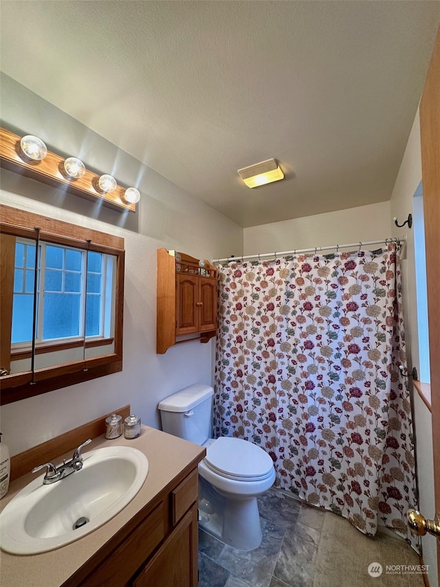 bathroom featuring a textured ceiling, vanity, toilet, and curtained shower