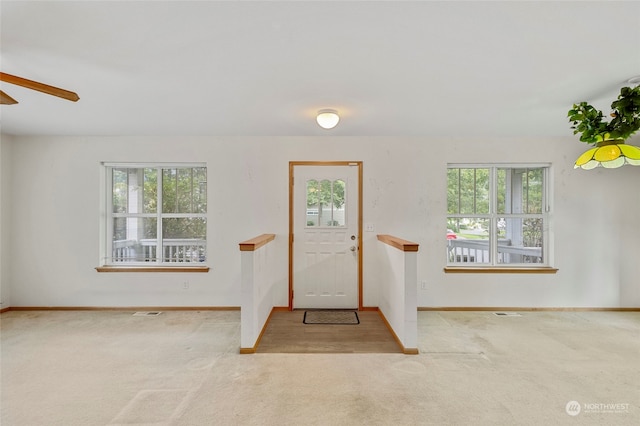 carpeted foyer entrance featuring ceiling fan and plenty of natural light