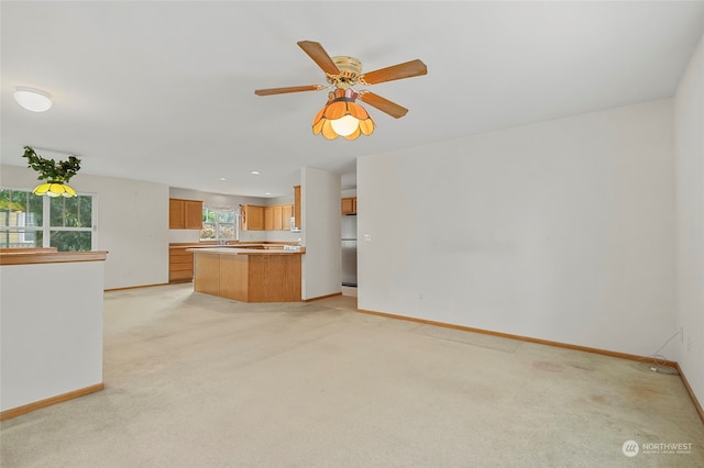 unfurnished living room featuring ceiling fan and light colored carpet