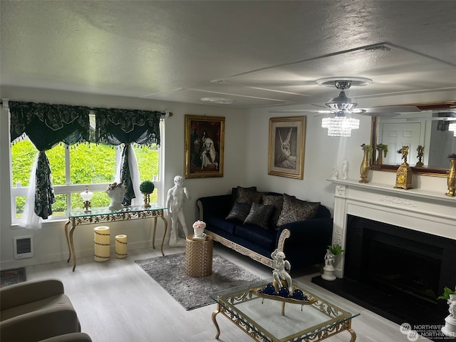 living room featuring ceiling fan, a textured ceiling, light wood-type flooring, and heating unit