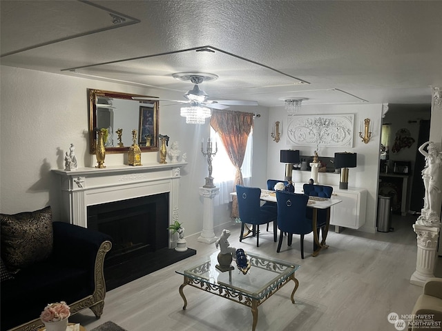 living room featuring light wood-type flooring, a textured ceiling, and ceiling fan